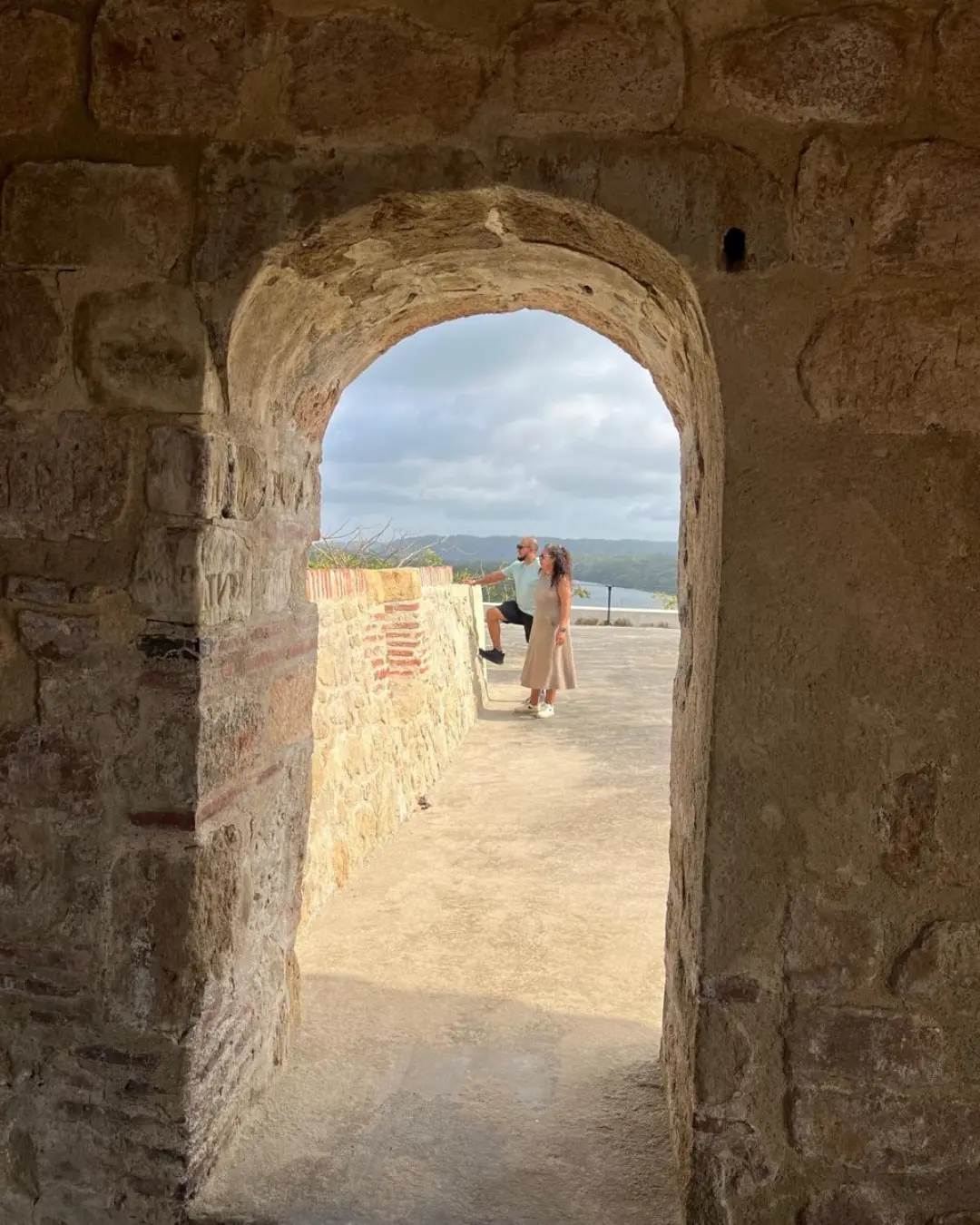 Karla Carrera con Geovanny mirando al horizonte enmarcados por un arco de piedra en Panamá